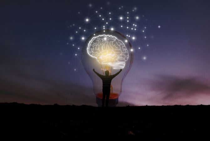 Persona frentte a una bombilla donde se ilumina un cerebro